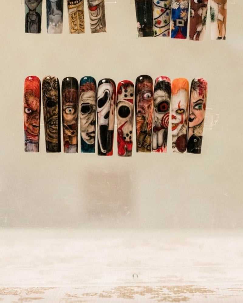 Nail art with horror-themed designs inspired by iconic movies, displayed on a beige background.