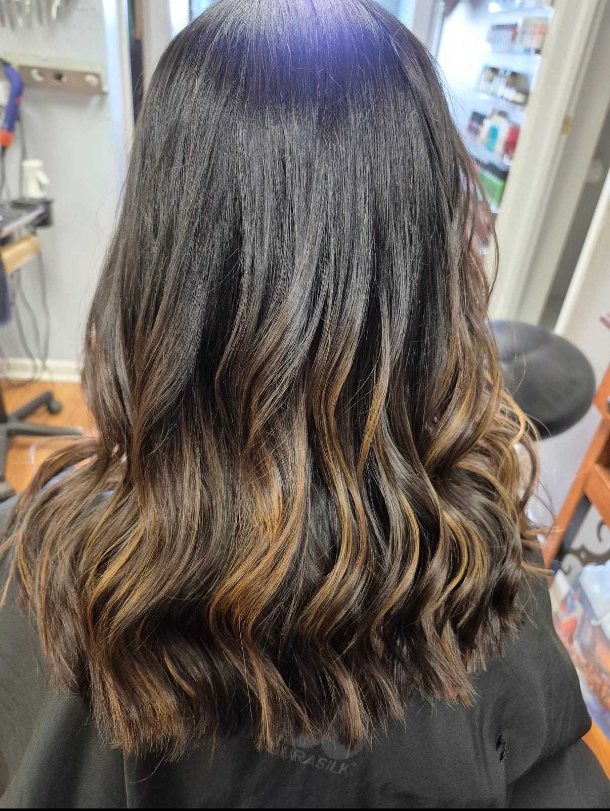 Wavy brown hair with caramel highlights, styled in a layered cut.