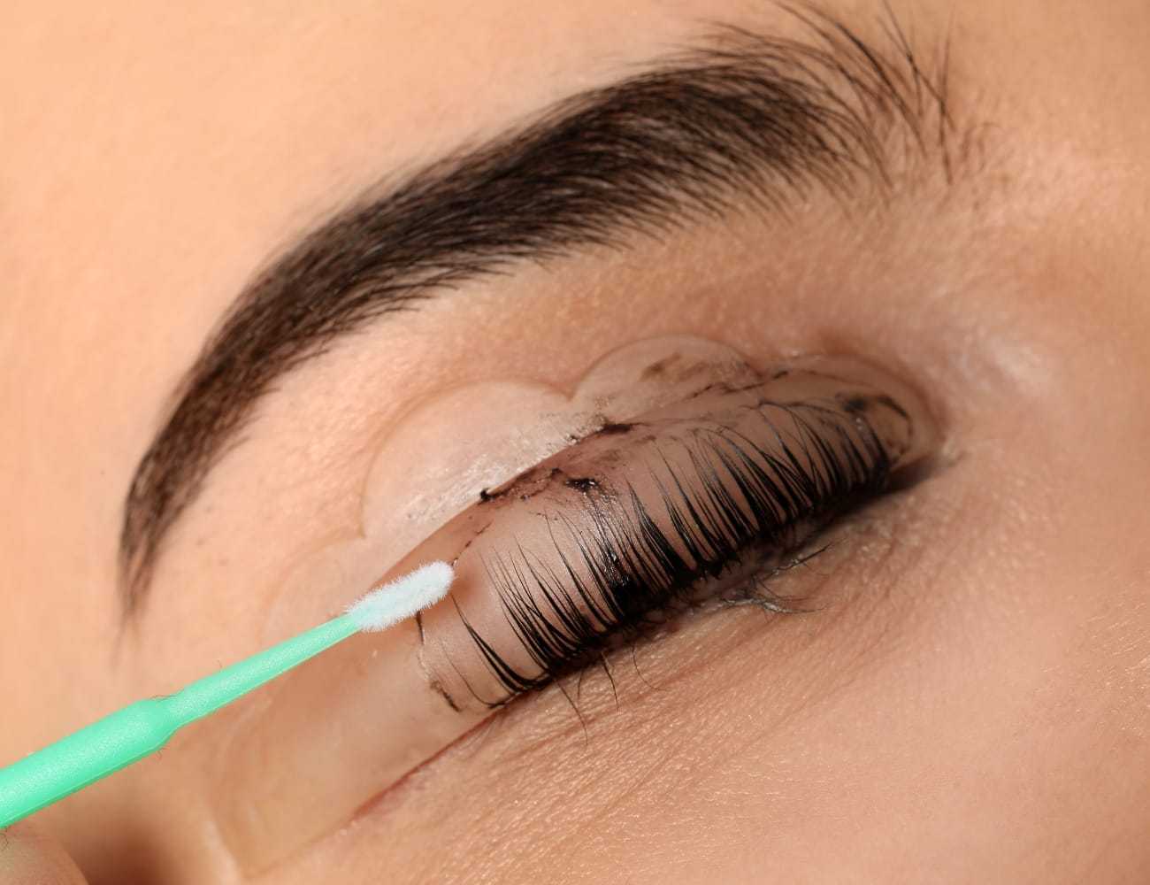 Eyelash curling with protective pads and applicator stick on a closed eye.